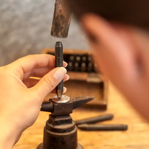 Schleifen einer fertigen Hundemarke an der Werkbank