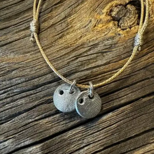 Silberne Schmuck-Anhänger mit Pfotenabdruck an Lederband