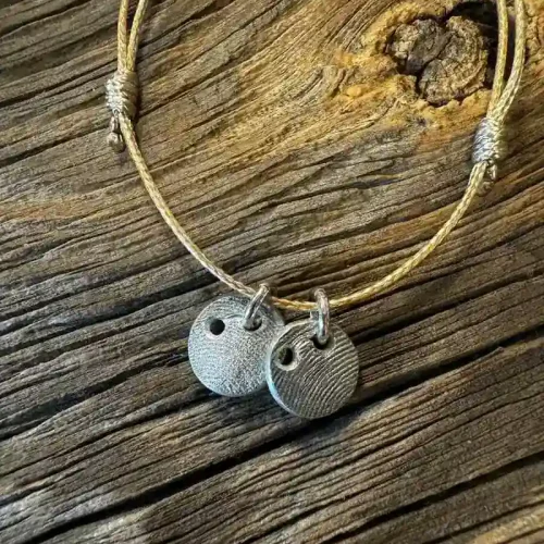 Silberne Schmuck-Anhänger mit Pfotenabdruck an Lederband